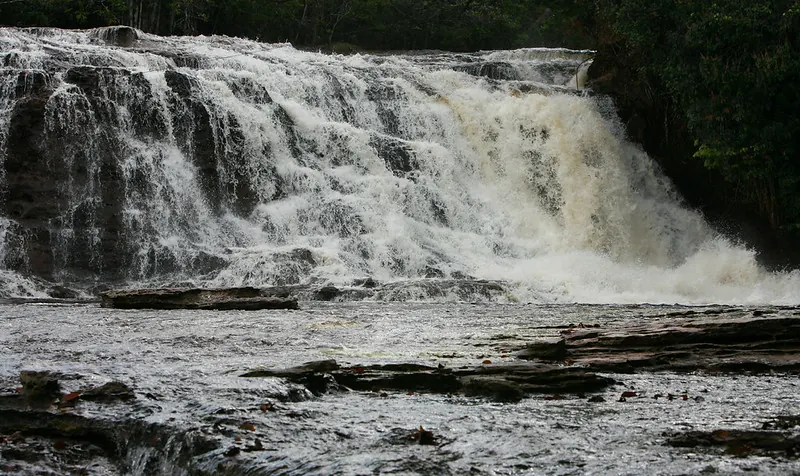 Cachoeira do Mutum, wide cascade over red sandstone into a natural pool, Presidente Figueiredo